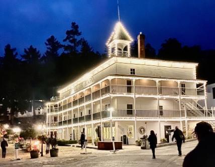 The Hotel de Haro at Roche Harbor in the evening, string lights tracing its three white verandas — the shuttle waits out front
